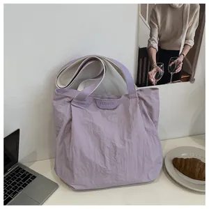 Détail du sac cabas lilas présentant une texture plissée et un écusson logo Fashion