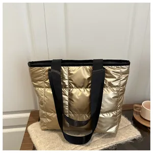 Detailed view of gold quilted tote bag with metallic finish and black shoulder straps