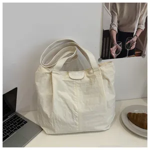Détail du grand sac cabas crème avec écusson FASHION et décor de bureau urbain