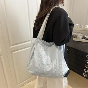 Grand sac cabas bleu clair texturé avec bandoulière porté par une femme style décontracté