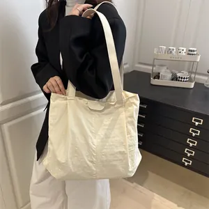 Grand sac cabas beige minimaliste en nylon froissé porté à l'épaule par un mannequin