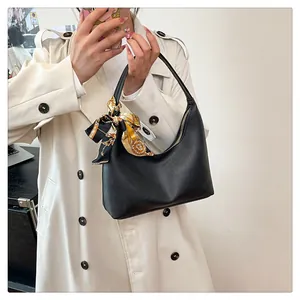 Detail of black pebbled leather crescent bag with decorative printed silk scarf on handle