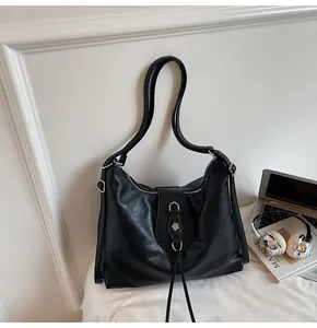 Detail of black leather tote bag with silver hardware on desk with laptop and books
