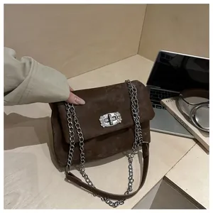 Détail du sac à bandoulière en daim marron avec boucle en diamant sur un bureau
