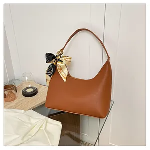 Detail of brown lychee texture leather hobo bag with vintage floral silk scarf handle