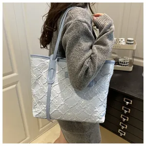 Dettaglio della borsa tote azzurra in tessuto strutturato con delicati ricami floreali