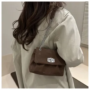 Détail d'un sac bandoulière en daim marron avec fermoir rotatif serti de diamants