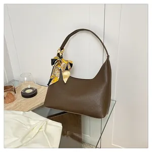 Detail of dark brown lychee leather crescent bag with decorative silk scarf on handle