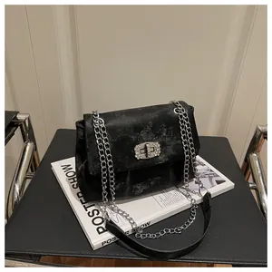 Détail du sac bandoulière en velours avec fermoir strass brillant et chaîne argentée