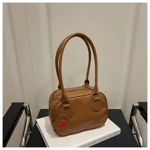 Dettaglio della borsa a mano marrone in pelle martellata con ciondolo a forma di cuore