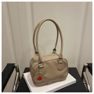 Dettaglio borsa a mano beige in similpelle a grana litchi con ciondolo a forma di cuore