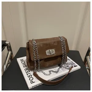 Détail du sac bandoulière en daim marron avec fermoir strass et chaîne argentée