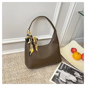 Detailed macro view of dark brown pebbled leather texture on crescent hobo bag