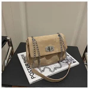Détail du sac à main en daim marron clair avec boucle en strass et bandoulière chaîne argentée