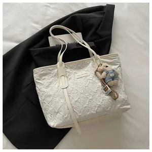 Dettaglio della borsa tote trapuntata crema con trama a rilievo e ciondolo a forma di orso