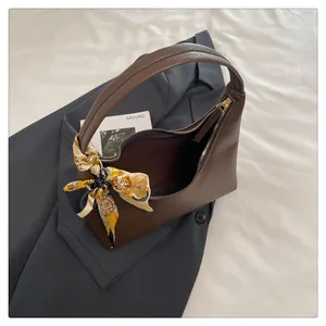Detail of dark brown lychee leather hobo bag with floral silk scarf on a grey blazer