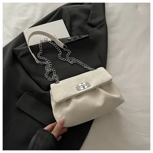 Détail du sac à chaîne beige avec fermoir rotatif métallique sur un tissu noir élégant