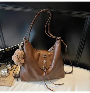 Detailed macro view of brown PU leather bag with metal flower clasp and plush bear charm