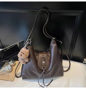 Detail of dark brown faux leather tote with silver floral buckle and cute plush dog charm