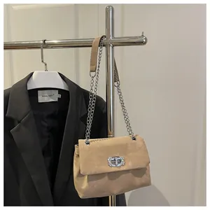 Détail du sac beige en daim avec bandoulière chaîne argentée et fermoir à strass