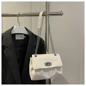 Détail du sac à chaîne blanc avec boucle en strass de luxe et cuir plissé élégant