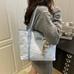 Borsa tote trapuntata celeste con ciondolo a forma di orso indossata da una modella