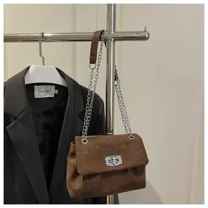 Détail du sac bandoulière en daim marron avec boucle en strass et chaîne argentée