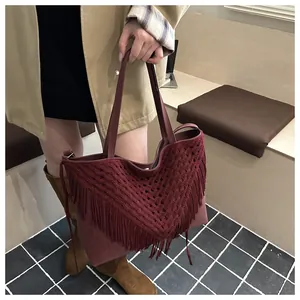 Detailed shot of burgundy tote bag featuring bohemian tassels and crochet hollow-out design