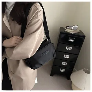 Close-up of minimalist black nylon crossbody bag with JINGPIN logo and fabric shoulder strap