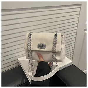 Gros plan sur un sac à chaîne crème avec une boucle fleurie en cristal et texture daim