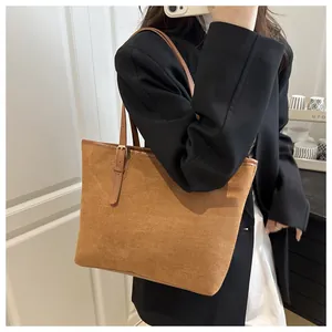 Detail of suede texture and leather strap with gold buckle on brown tote bag