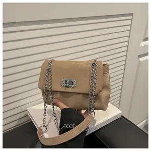 Gros plan d'un sac à main kaki en daim avec fermoir rotatif en strass et bandoulière chaîne