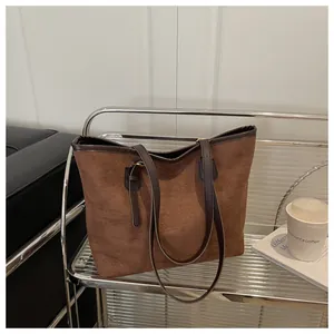 Macro detail of the brown suede texture and leather straps on the minimalist tote bag