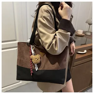 Detalle del bolso tote bicolor en ante con triángulo metálico y colgante de osito