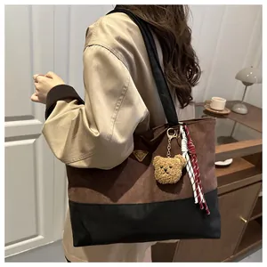 Detalle de bolso tote bicolor efecto ante con osito de peluche y cinta de cuadros