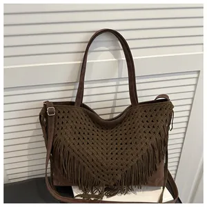 Close-up of brown woven tote bag with V-shaped patterns and long tassels on white background