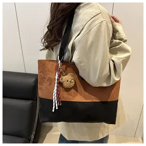 Vista detallada del bolso tote bicolor en ante marrón con colgante de oso de peluche