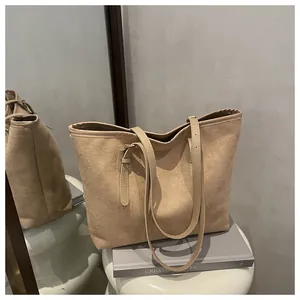 Detail of minimalist apricot tote bag with suede texture and metal buckle on books
