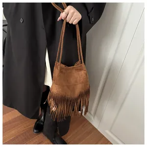 Détail d'un sac seau bohème en daim marron avec de longues franges sur un mannequin