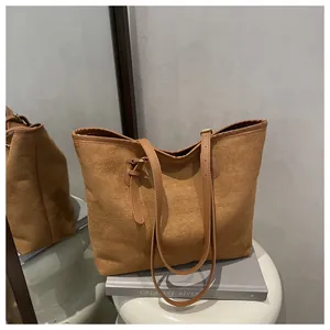 Detail of a brown canvas tote bag with adjustable leather straps in a minimalist setting