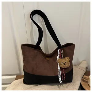 Detalle de bolso tote bicolor en gamuza con un adorable colgante de osito de peluche