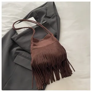Vue détaillée du sac seau en daim marron foncé avec de longues franges et une bandoulière