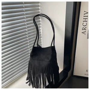 Gros plan d'un sac seau noir à franges avec texture en daim et détails de glands