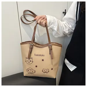 Close-up of khaki bucket bag with cute cat prints and dark brown contrast handle