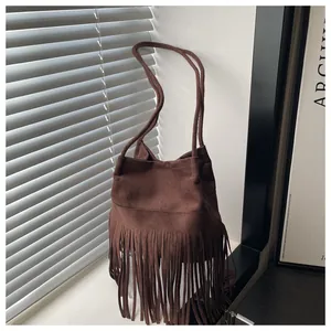 Détails d'un sac seau bohème en daim marron foncé avec de longues franges et une fine bandoulière