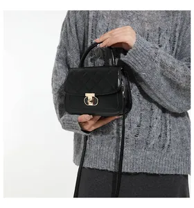Detail van zwarte gewatteerde crossbodytas met gouden slot en leren riem