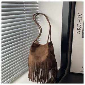 Détail du sac seau en daim marron foncé avec de longues franges et texture cuir premium