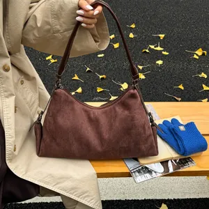 Close-up of deep brown suede shoulder bag with zipper detail in autumn setting