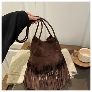 Détail du sac seau en daim marron foncé avec de longues franges bohèmes et poignée en corde