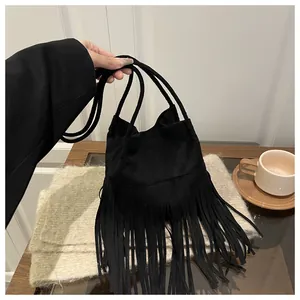 Détail d'un sac seau noir en daim avec franges porté dans un cadre élégant de café